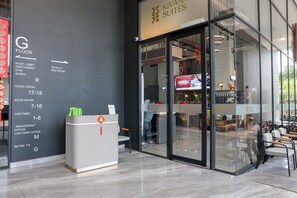 Bancada de recepção de hotel com placa indicando comodidades e números de quartos.