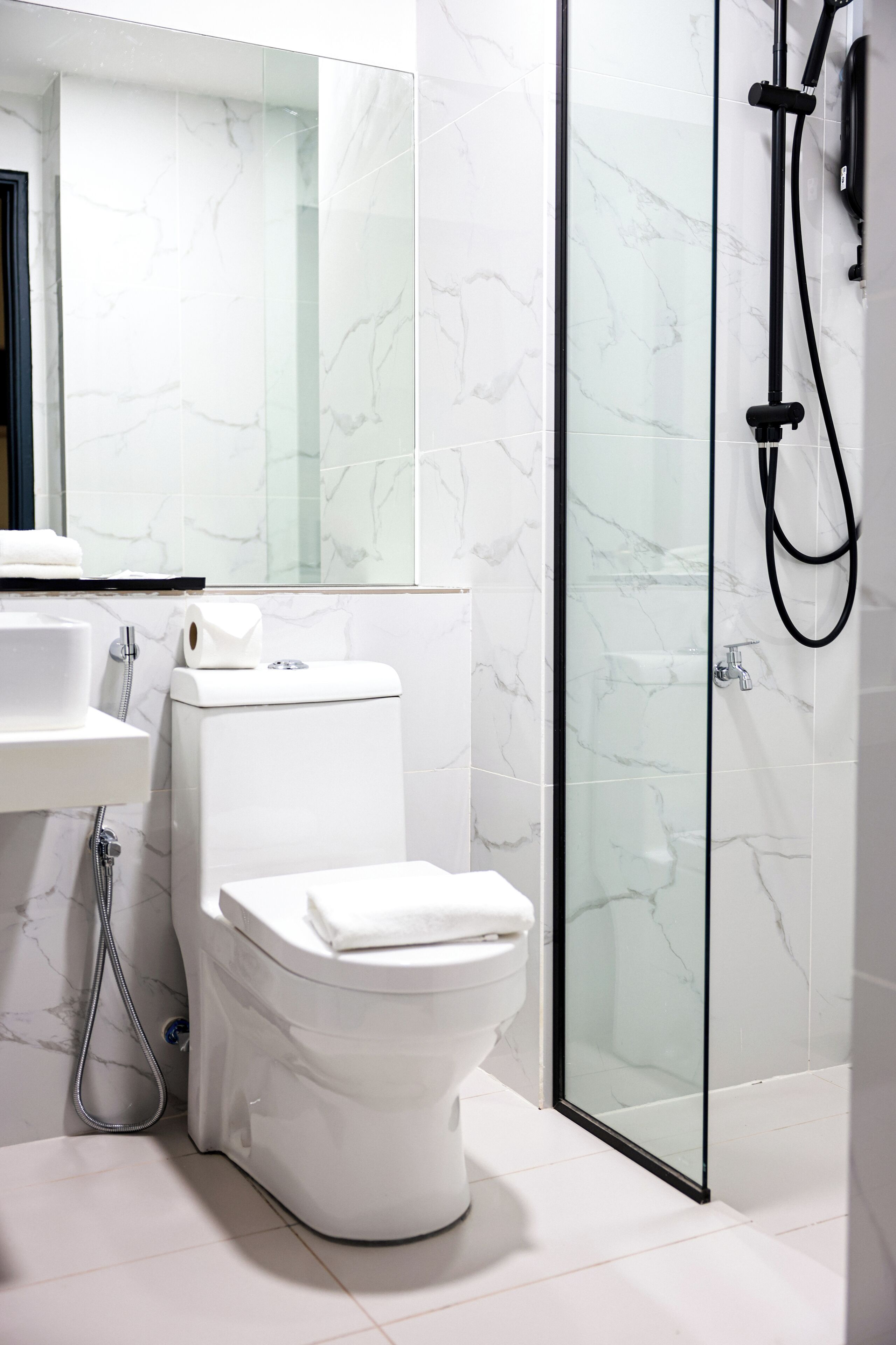Un baño moderno con inodoro, ducha de vidrio y lavamanos blanco.
