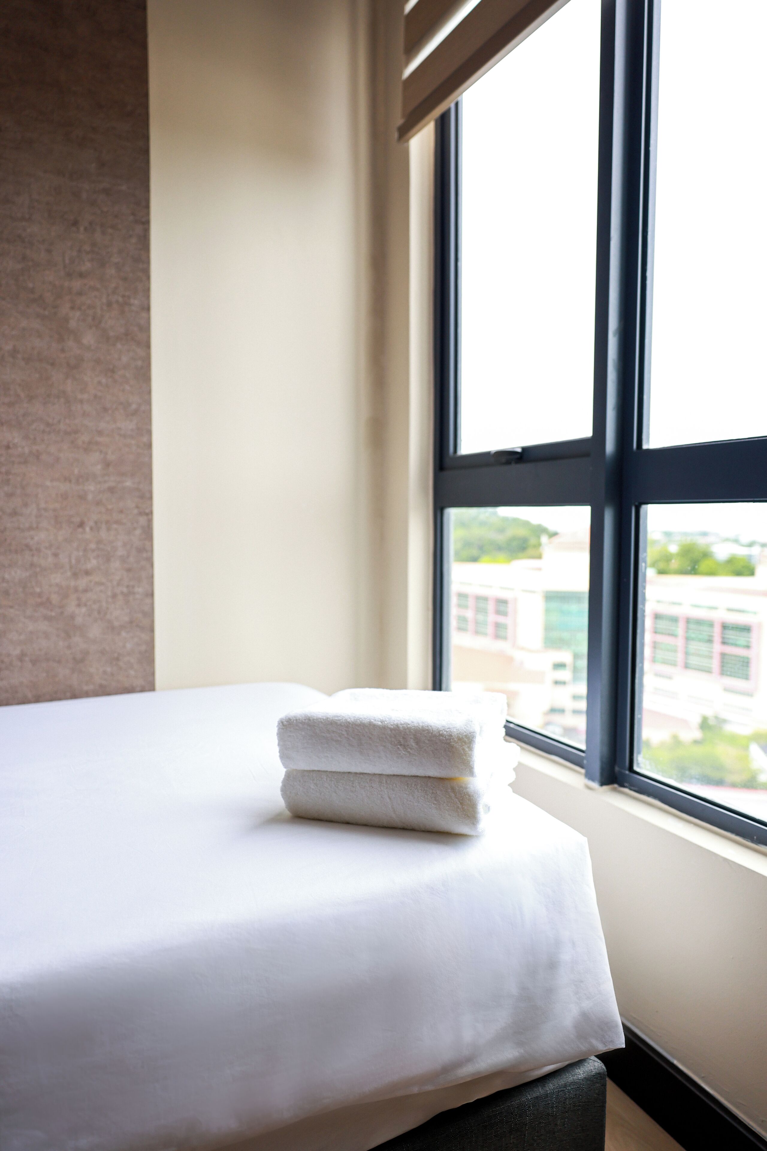 Een hotelkamer met een bed, een raam en uitzicht op gebouwen.