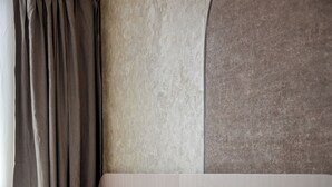 Une chambre d’hôtel avec un lit, des oreillers, une tête de lit et des rideaux.