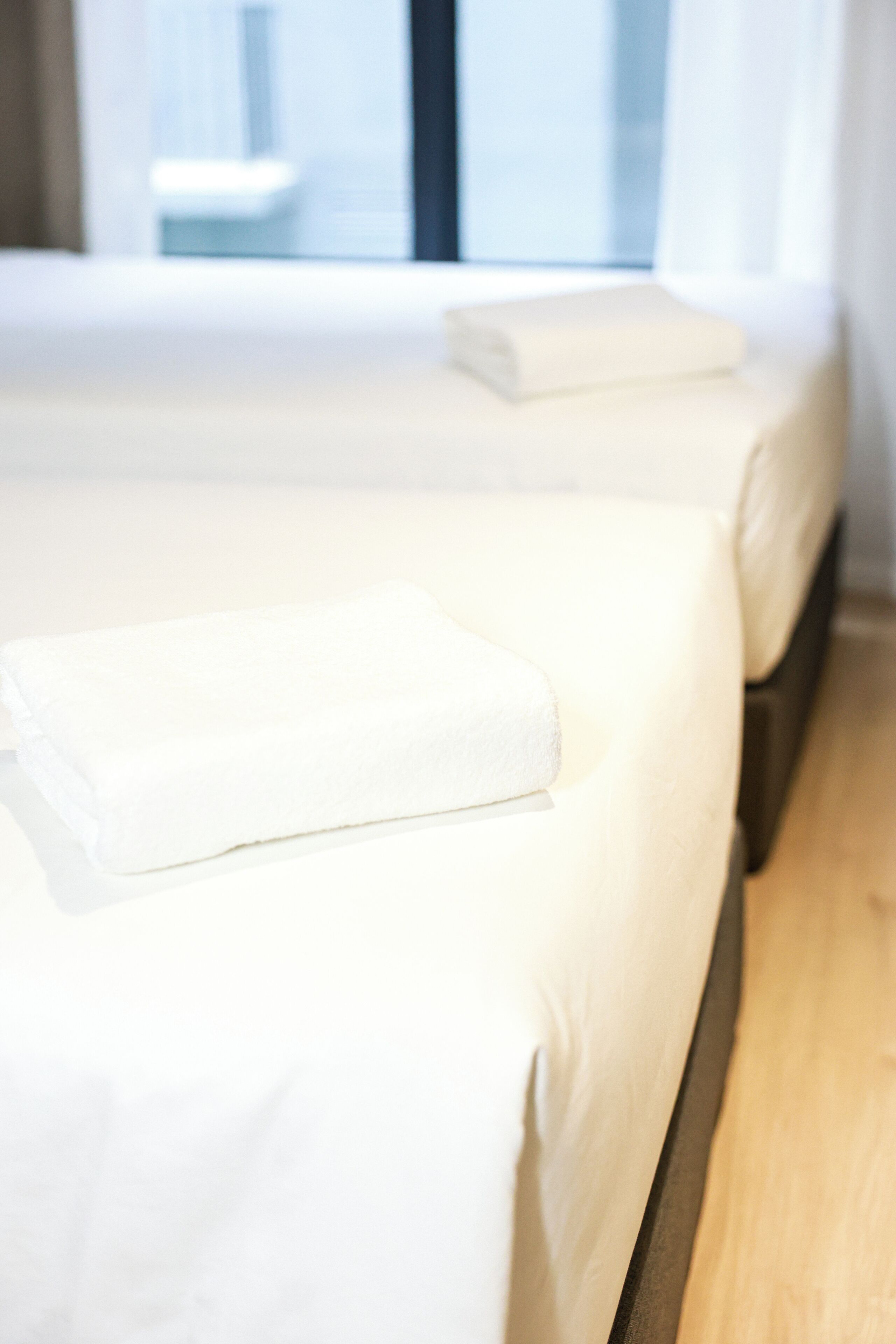 A hotel room with two beds, each with white linens and a neatly folded towel.