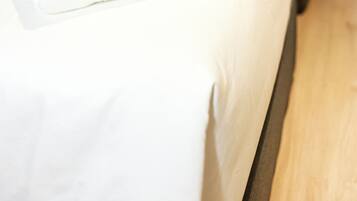 A hotel room with two beds, each with white linens and a neatly folded towel.