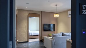 Une chambre d’hôtel moderne équipée d’un lit, d’un canapé, d’une télévision et d’une petite table.