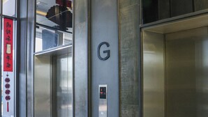 Un ascenseur avec une finition métallique, un téléphone d’urgence fixé au mur et une poubelle.