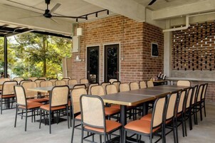 Un área de comedor al aire libre con paredes de ladrillo, varias mesas y sillas.