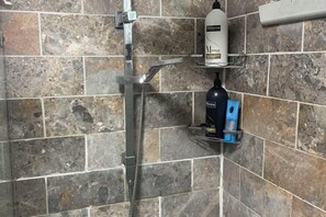 A shower with a handheld showerhead, a bottle of shampoo, and a soap dispenser on a shelf. - 3 Bed room Villa 19 Mins to Melbourne center (Laverton)