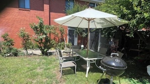 A patio with a table and chairs, a grill, and an umbrella. - 3 Bed room Villa 19 Mins to Melbourne center (Laverton)