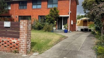 A two-story brick house with a front entrance, a small front yard, and a visible mailbox.