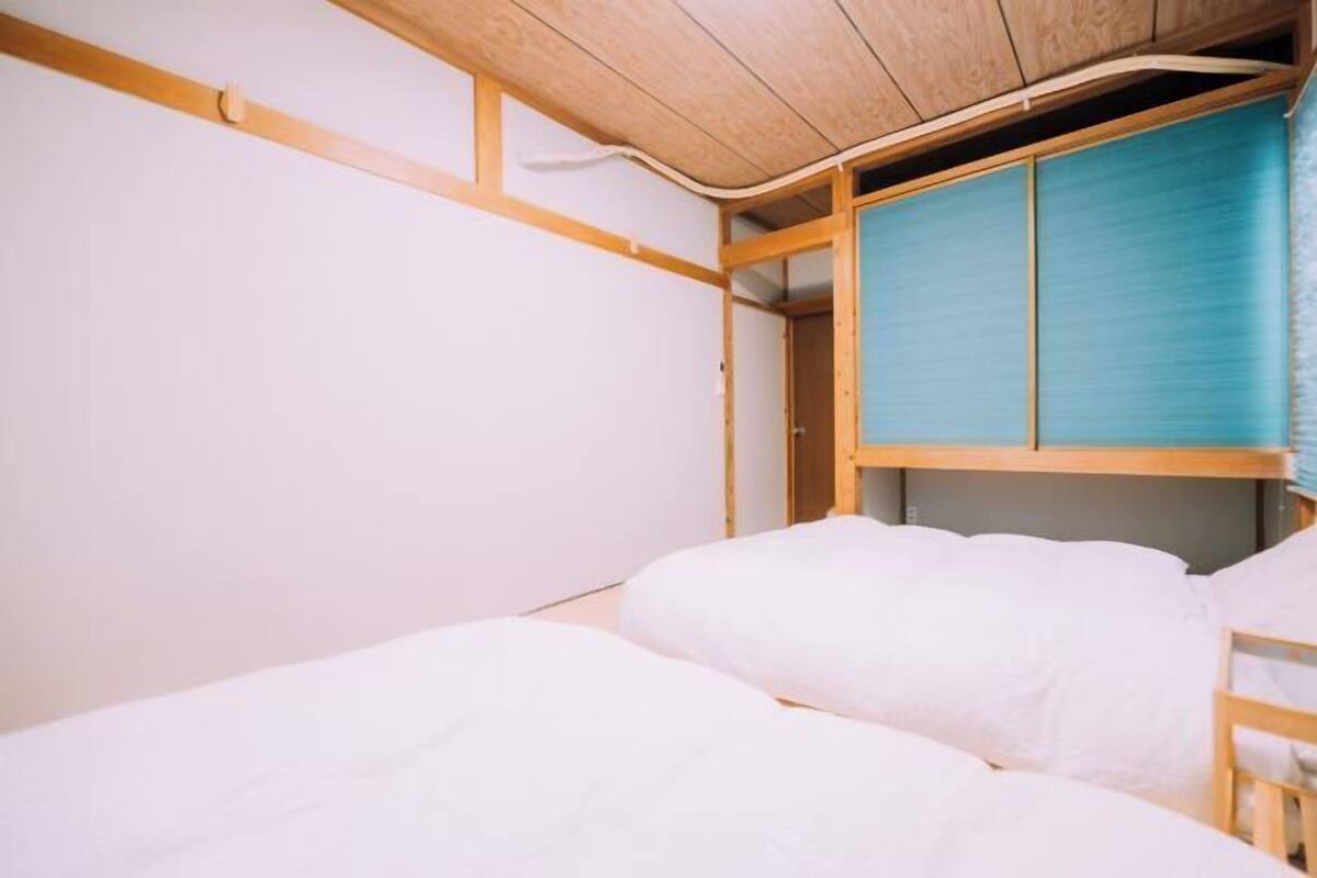 A room with a bunk bed, wooden ceiling, and a blue sliding door.