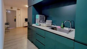 Una cocina moderna con armarios color aguamarina, encimera blanca y pileta de acero inoxidable.