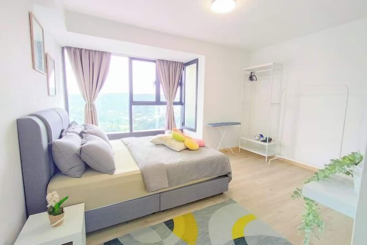A bedroom with a bed, a desk, a shower, and a view of the outdoors.