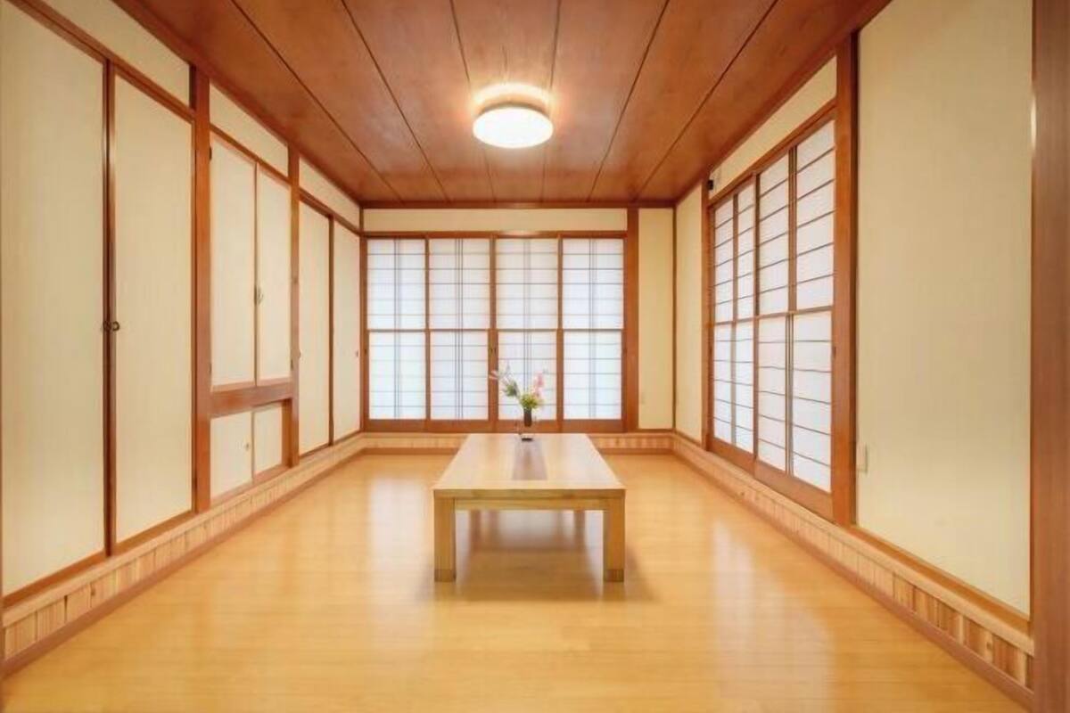 Une pièce de style japonais traditionnel, avec un sol recouvert de tatamis, des portes coulissantes et une table centrale.