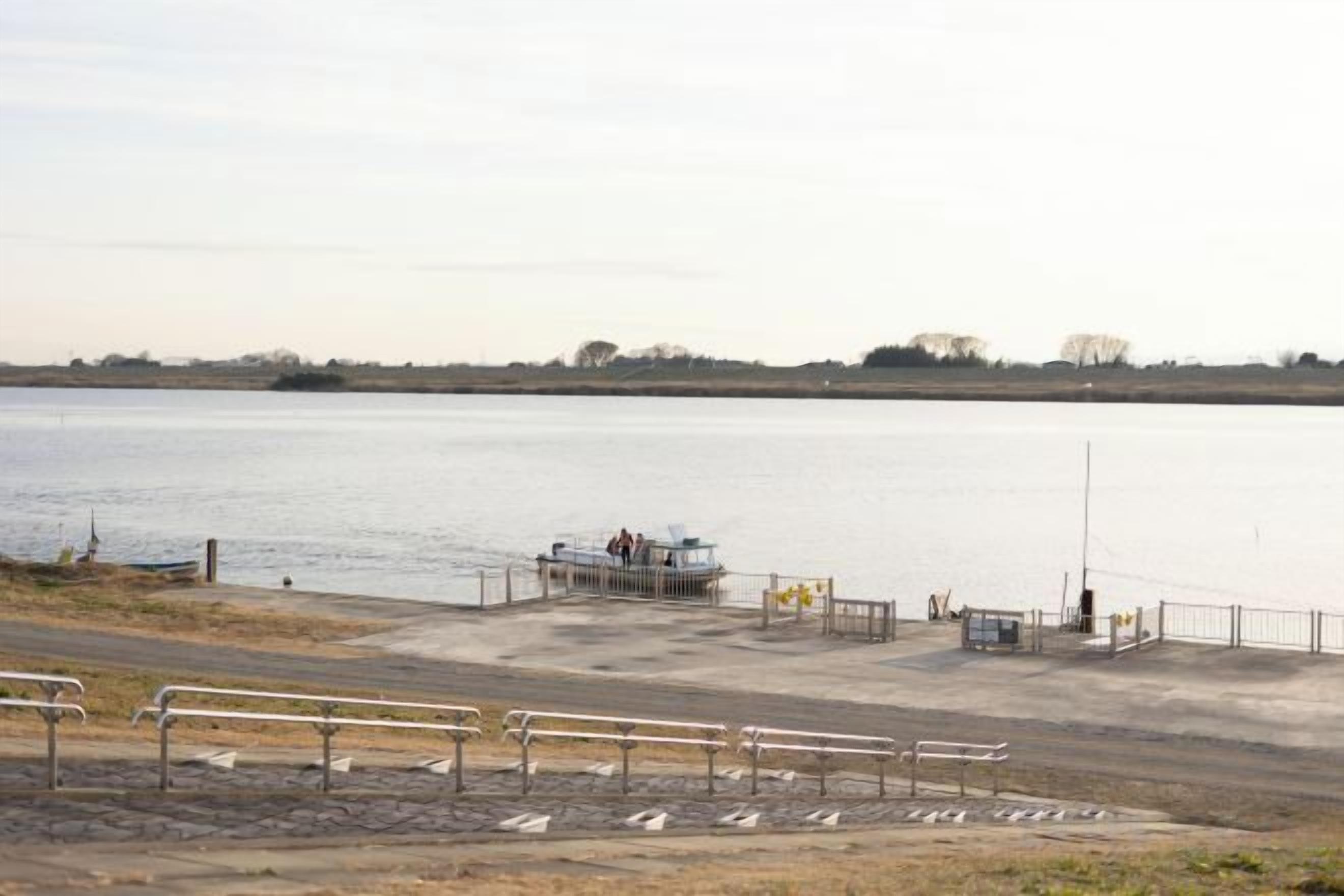 A waterfront area with a dock, a small building, and a fenced walkway.