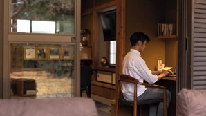 A person seated at a desk in a room with a window, a bookshelf, and a television. - TEMPLESTAY ZENSŌ (Chiyoda)