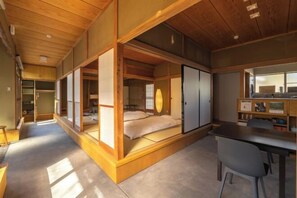 Een traditionele Japanse kamer met tatami vloerbedekking, een laag houten bureau en een bed met futon.