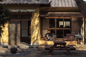 Una casa tradicional japonesa con fachada de madera, una puerta corredera y un ventanal grande.