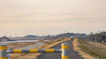 A rural road with a person walking, a barrier with yellow and gray stripes, and distant power lines.