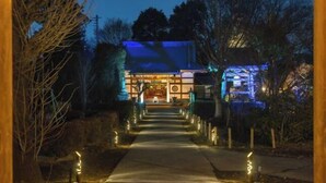A pathway leading to a traditional building with a blue roof, surrounded by trees and illuminated by pathway lights. - TEMPLESTAY ZENSŌ (Chiyoda)