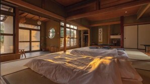 A traditional Japanese room with tatami flooring, a large bed, sliding doors, and a view of the outdoors. - TEMPLESTAY ZENSŌ (Chiyoda)