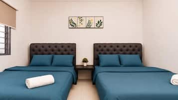 A room with two beds, each with a dark headboard and teal bedding. There is a small table with a plant between the beds.
