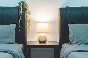 Una cama con una mesita de noche, una lámpara y una planta.
