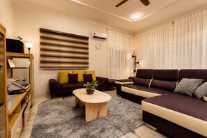A modern living room with a sofa, a coffee table, and a TV. - Batu Pahat Sri Jaya Villa 4BR 18pax (Simpang Kanan)