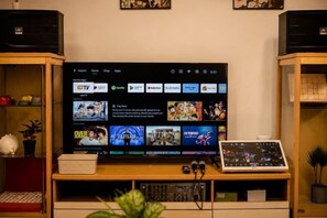 A television mounted on a wooden stand with a digital interface displaying various streaming services.