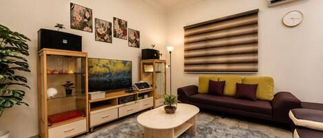 Una sala de estar con sofá, mesa de centro, televisor y mueble de entretenimiento.
