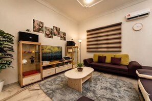 A living room with a sofa, coffee table, TV, and entertainment unit. - Batu Pahat Sri Jaya Villa 4BR 18pax (Simpang Kanan)