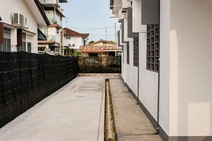 A narrow alleyway between buildings with a concrete path and a black fence on one side. - Batu Pahat Sri Jaya Villa 4BR 18pax (Simpang Kanan)