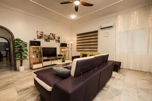A modern living room with a sofa, TV, and entertainment unit. - Batu Pahat Sri Jaya Villa 4BR 18pax (Simpang Kanan)