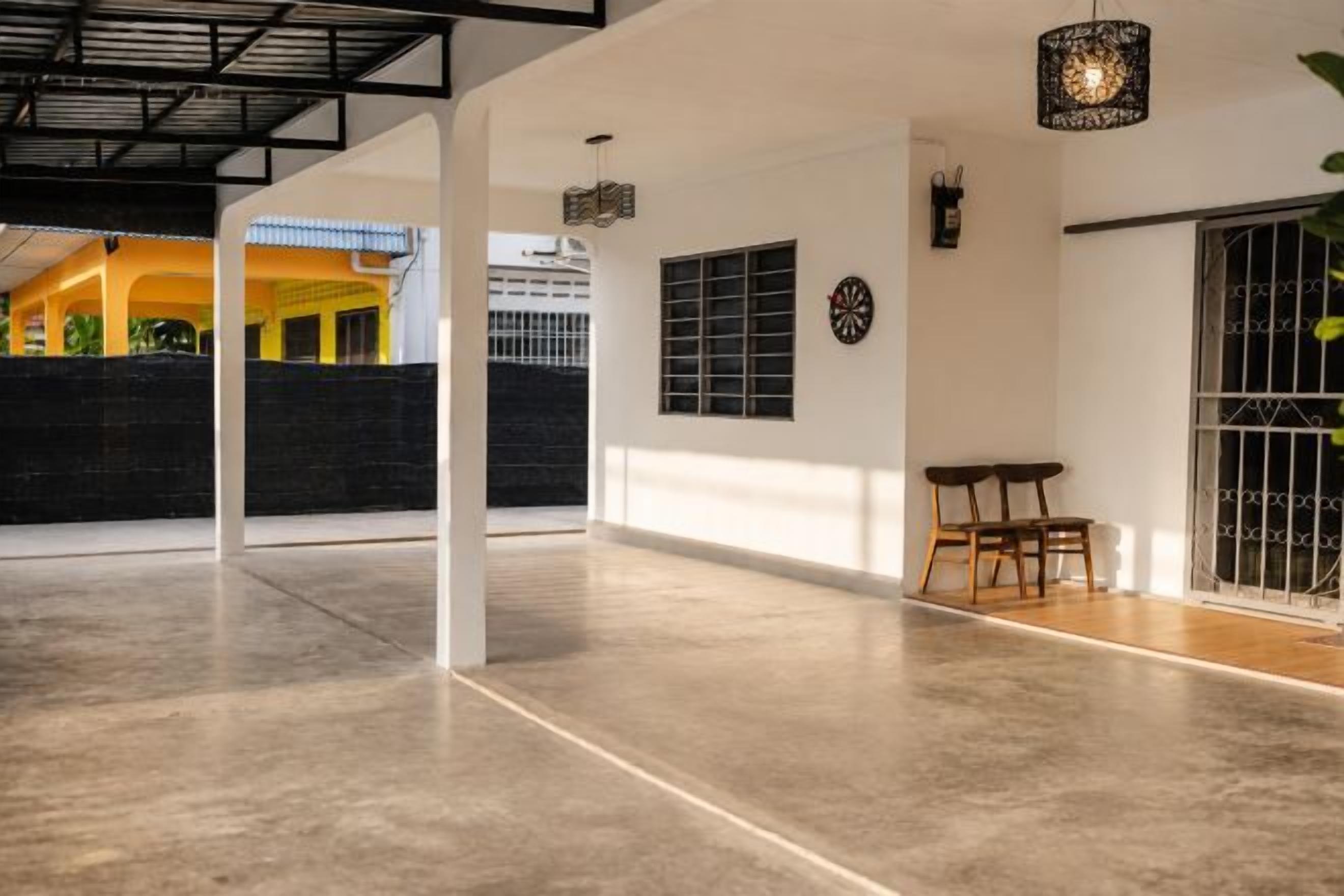 A spacious indoor area with a concrete floor, a dining table with chairs, a wall-mounted clock, and a decorative light fixture.