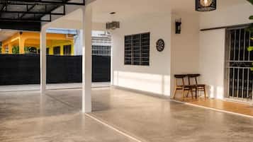 A spacious indoor area with a concrete floor, a dining table with chairs, a wall-mounted clock, and a decorative light fixture.