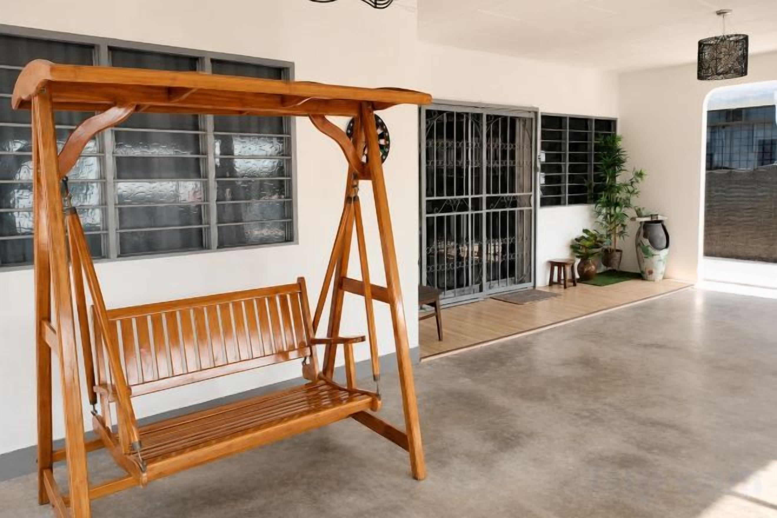 Un conjunto de columpios de madera en un espacio amplio con ventanas grandes y piso de concreto.