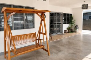 A wooden swing set in a spacious room with large windows and a concrete floor. - Batu Pahat Sri Jaya Villa 4BR 18pax (Simpang Kanan)