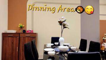A dining area with a table set for four, a vase of flowers, and a wall with the text 'Dining Area' and emojis.