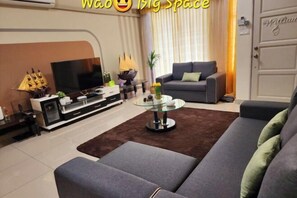 A modern living room with a grey sofa, a glass coffee table, and a flat-screen TV. - Landed House #Semenyih #Cozy #BBQ (Semenyih)