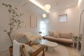 Un salon moderne avec un canapé, un fauteuil, une table basse et une plante en pot.