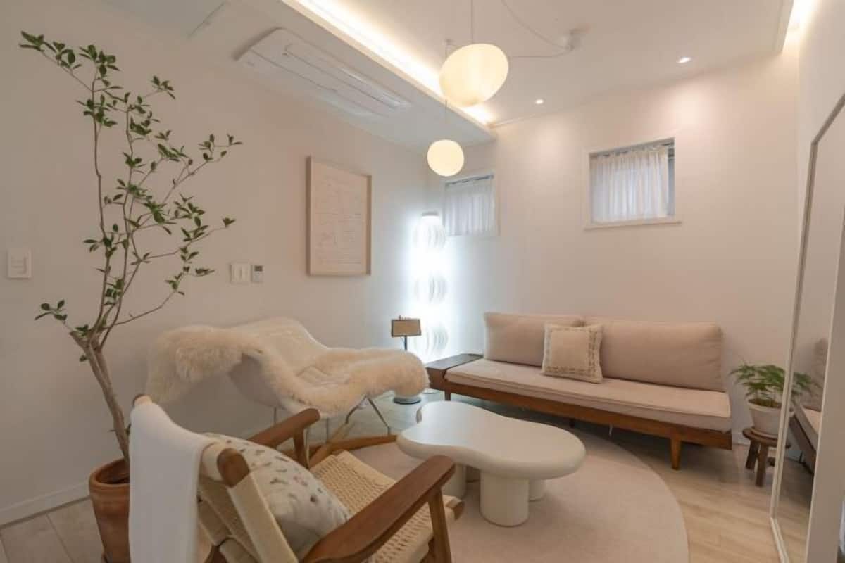 A modern living room with a sofa, a chair, a small table, and a potted plant.