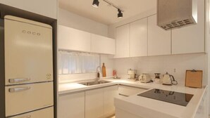 A compact kitchen with a built-in refrigerator, a sink, and a stove. - Mon Monde Aewol (Jeju)