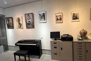 A room with a piano, a desk with a computer, and a cabinet. There are framed pictures on the wall. - Guesthouse Atelier Ten (Osaka)