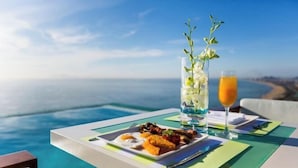 A dining table with a meal and drinks, overlooking a coastal view. - A La Carte Beachfront Lovers Bliss Retreat Studio (Da Nang)