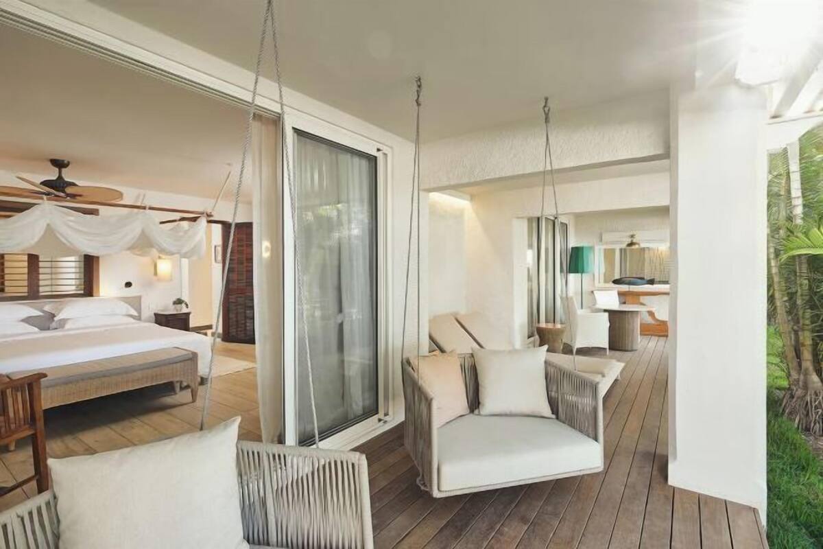 Een slaapkamer met een bed, een hangstoel en een groot raam.