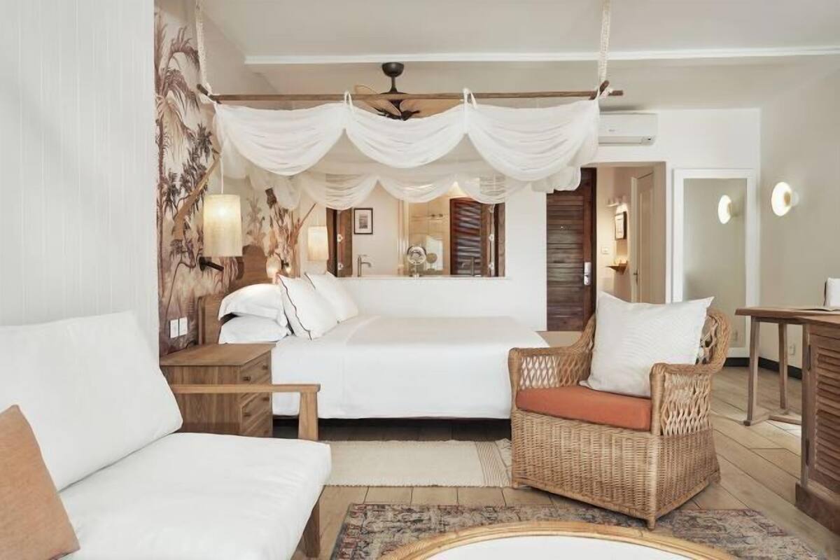 Een slaapkamer met een bed, twee nachtkastjes, een stoel, een vloerkleed en een plafondventilator.