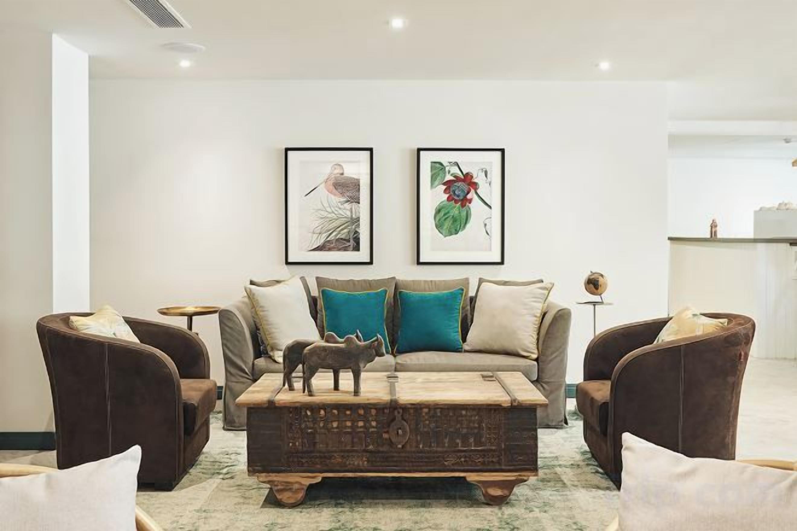 A modern living room with a sofa, two armchairs, a coffee table, and artwork on the wall.