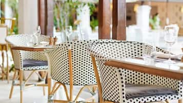 A restaurant with wicker chairs and tables, some with cushions.