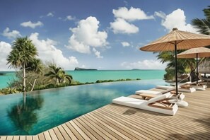 Une piscine à débordement avec une terrasse en bois, des chaises longues et des parasols, offrant une vue imprenable sur une mer turquoise et un ciel dégagé.