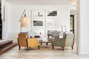 Una sala de estar con piso a cuadros, una mesita de centro y tres sillones.