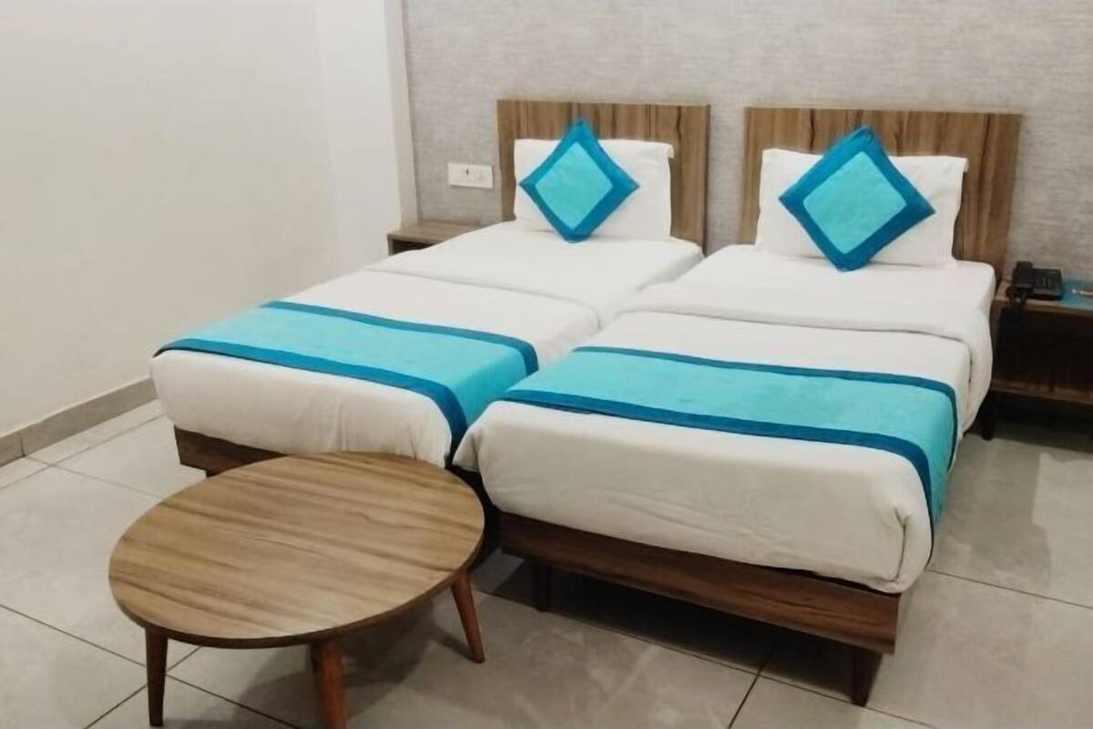 A hotel room with two beds, a round wooden table, and a nightstand with a phone.