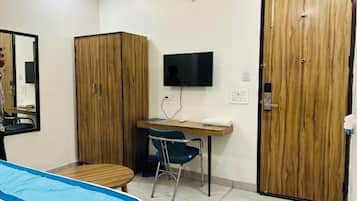A room with a bed, a desk, a chair, a TV, and two wardrobes.